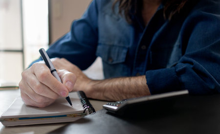 Close up shot of engineer at his desk.Horizontal shot of hands of a man writingの写真素材