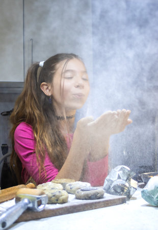 Funny gir preparing dough for cookies at the kitchen at home. Vertical high quality photo.National cookie day. Used for cooking recipe promotions.の写真素材
