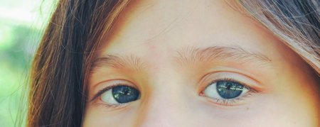 Horizontal very close up image of girl looking at camera with clear eyes.Nice blue eyes of caucasian girl with deep gaze.Vintage style photography, antiqueの写真素材