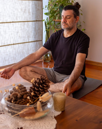 Man doing yoga and meditating on an exercise mat with his eyes closed. Concept of breathing, meditation and well-being. Space for text.Exercise and meditation at homeの写真素材
