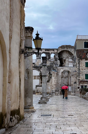 Tourist walking in Diocletian Palace under the rain. Tourist sites full of history. Split City declared World Heritage Site. Images for travel and tourism agencies. Copy spaceの写真素材
