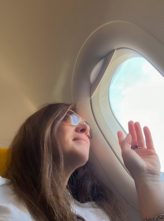 Happy woman on vacation, Exploring the world from the airplane window.An air travel scene, perfect...