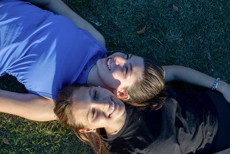 Smiling teen relaxing happily after workout in park, conveying a sense of fun and friendship. Horizontal shot. Casual sport outfit. Healthy lifestyle conceptの写真素材