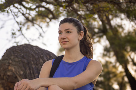 Girl spending a relaxing time in nature, park in blurred background. Horizontal real picture....