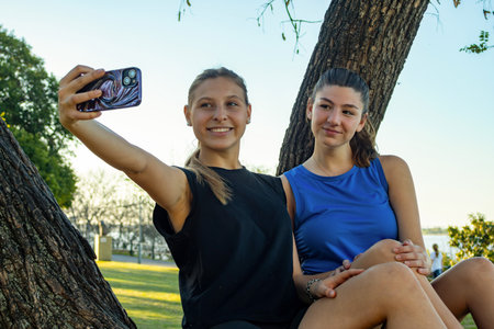 Playful young friends taking selfie outdoors at sunset, carefree teenagers in nature.Perfect for social media campaigns, lifestyle blogs, and youth marketing projects.Horizontal real pictureの写真素材