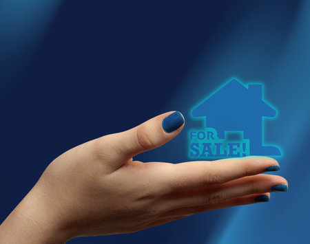 Female hand holding house icon representing real estate market Great for real estate agencies and housing campaigns.Copy space.の写真素材