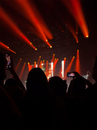 Fans cheering and taking pictures at a concert. Public enjoying and filming the music recital. Vertical shotの写真素材