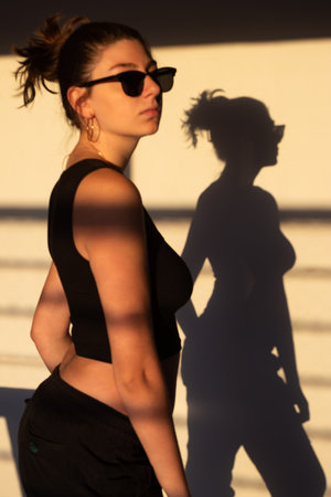 Millennial girl posing stylishly at sunset, simple and striking, ideal for fashion photography and images related to teen culture.の写真素材