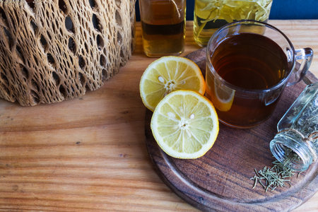 Hot herbal tea on a wooden board, featuring lemon slices,botanical infusions and dried rosmary, promoting wellness and holistic care. Copy spaceの写真素材