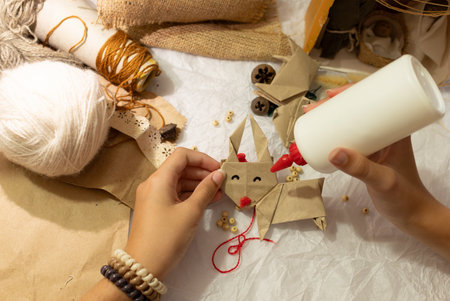 Woman hands preparing Christmas ornaments,surrounded by craft supplies. Concept of material care and...
