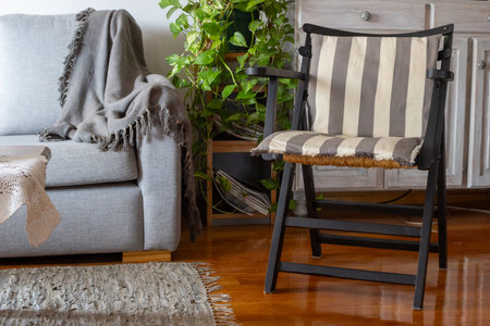 Living room interior featuring a comfortable sofa, striped armchair, green houseplants, and home decorの写真素材