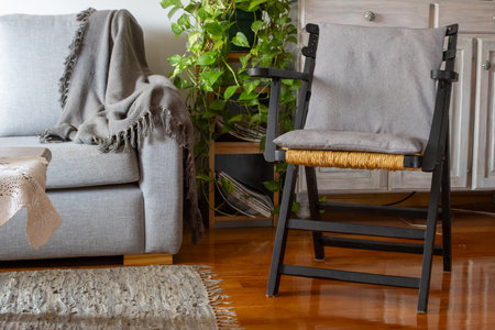 Modern rustic living room interior featuring a comfortable sofa with a throw blanket, a rustic chair with a woven straw seat.の写真素材