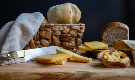 Rustic table setting showcasing a variety of yellow and white cheese slices with a vintage knife. Perfect for cooking magazines, brochures, and food advertisements.の写真素材