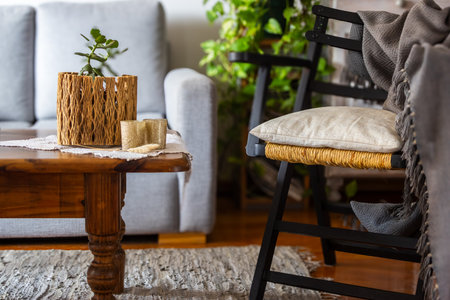 Country style living room interior with a wooden chair and coffee table featuring some books and a rustic pot with succulent. Natural light, horizontal real picture. Perfect for magazines on interior design.の写真素材