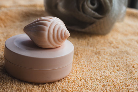 Seashell shaped soap resting on a pink container, presenting a comforting scene for self care, beauty rituals, and relaxing spa experiences with natural cosmetic productsの写真素材