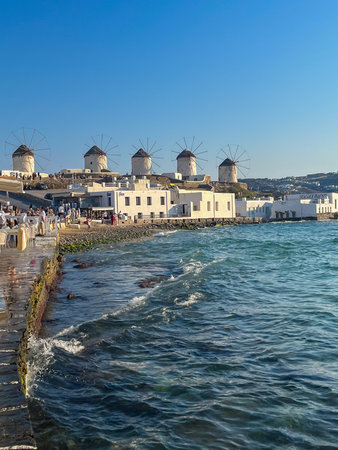 Traditional mykonos windmills with vibrant blue details and thatch roof, evoking greek island...