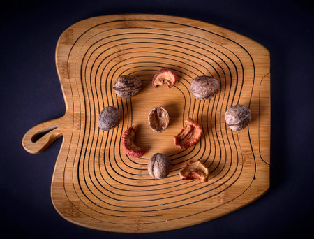 Walnuts and dried fruits on a wooden board in apple form, top view