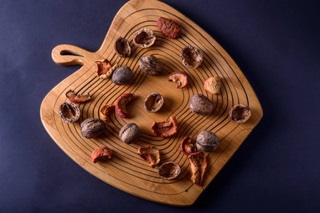 Walnuts and dried fruits on a wooden board in apple form, top viewの写真素材