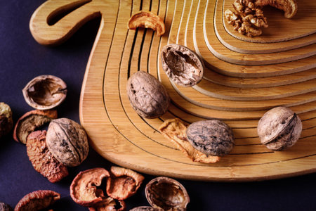 Walnuts and dried fruits on a wooden support in the form of a pyramid, blue background