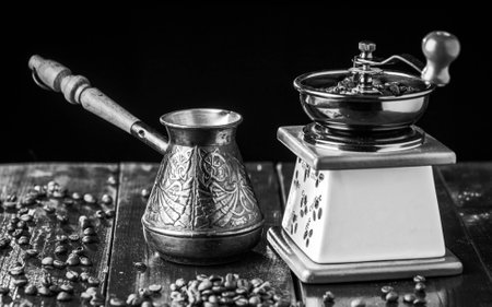 Mechanical coffee grinder is filled width coffee beans and old copper cezve and coffee beans. Black and white.の写真素材