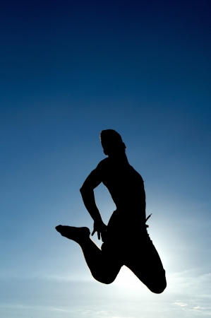 teenage boy jumping with blue sky as backgroundの写真素材