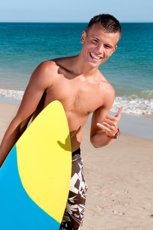 teenage boy posing with surf board in the beachの写真素材