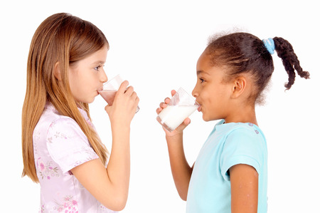 little girls holding glass of milk isolated in whiteの写真素材