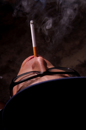 young guy smoking with black backgroundの写真素材