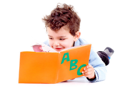 little boy reading a book isolated in whiteの写真素材