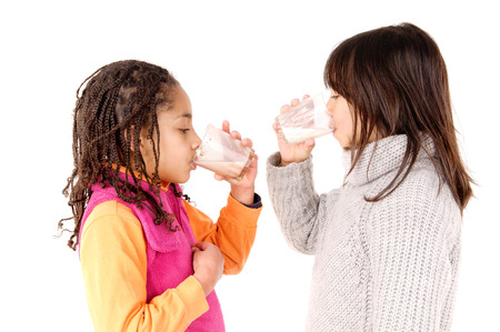 little girls drinking milk isolated in white backgroundの写真素材