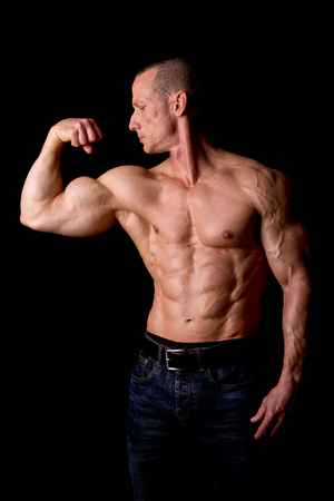 fit muscular man posing isolated on a dark backgroundの写真素材