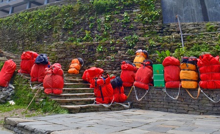 Huge red backpacks for mountain expedition on stairs. Porter Mountaineering equipment. Nepal, Annapurna Base Camp track.の写真素材