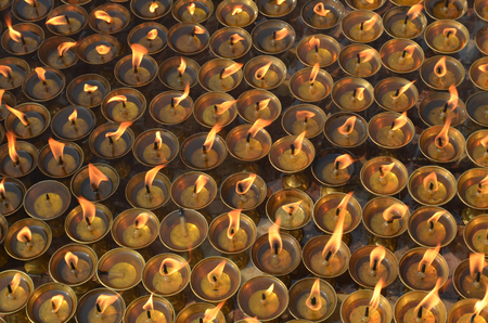 Many burning oil lighting up candles / lamps in buddhist temple - Great stupa Bodnath in Kathmandu, Nepal. For ritual, meditation, consciousness, praying, faith.の写真素材