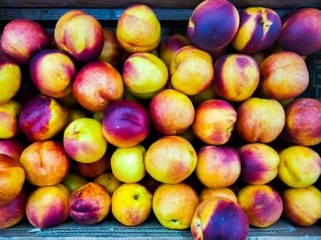 Background of ripe nectarines in the market. Ripe fruits on the counter. Mの写真素材