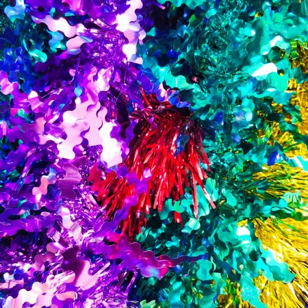 Bright christmas background from colored tinsel. Colored metal foil. Close-up. View from above.