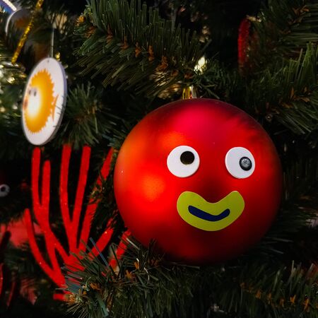Red ball with emotions hanging on a Christmas tree. New Year's toy. Card.の写真素材