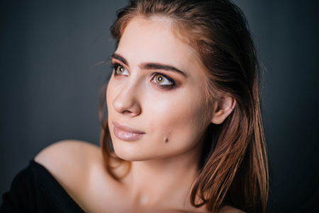 beauty portrait. Studio portrait of a beautiful girl on a gray background. Good make-up. Face closeupの写真素材