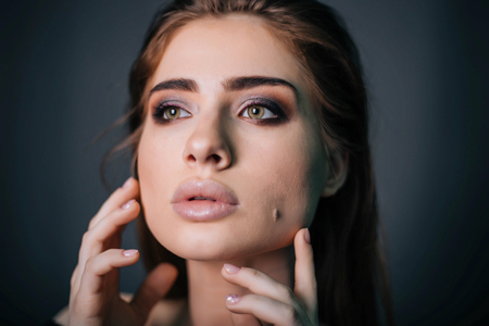 beauty portrait. Studio portrait of a beautiful girl on a gray background. Good make-up. Face closeupの写真素材
