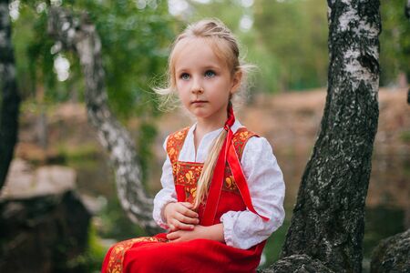 Little girl with white hair in a red, Slavic sundress.の写真素材