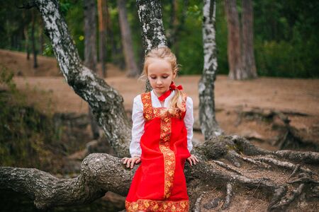 Little girl with white hair in a red, Slavic sundress.の写真素材