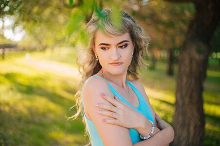 Beautiful girl on a walk in the park. Blonde in a blue t-shirt in the forest.の写真素材