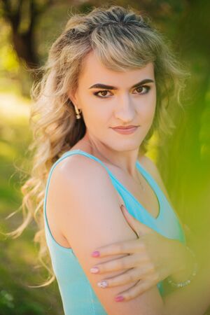 Beautiful girl on a walk in the park. Blonde in a blue t-shirt in the forest.の写真素材