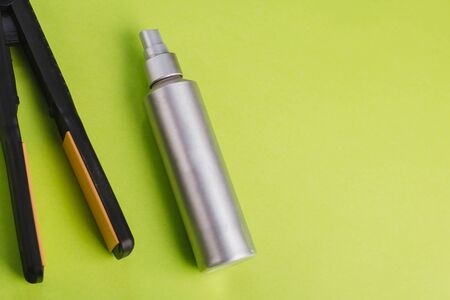 Black Hair Straighteners on a green background and a silver bottle. Barber tool.の写真素材