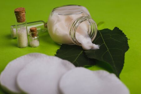 Eco cosmetics. A jar of white cream and the leaves of the tree on a green background. Skin care.の写真素材