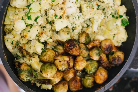 Potatoes with greens in a pan and fried Brussels sprouts.の写真素材