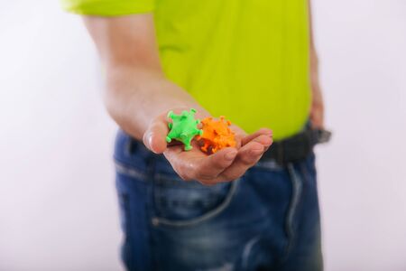 A guy in a green T-shirt holds out his hand with a coronavirus. Dirty hands.の写真素材