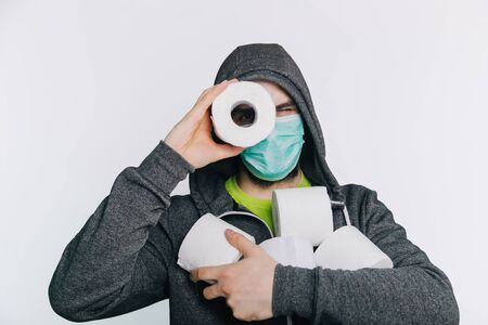 A guy in a gray sweatshirt and with rolls of toilet paper instead of eyes stands on a white background. The excitement during quarantine for coronavirus. Rotaviruses in men.の写真素材