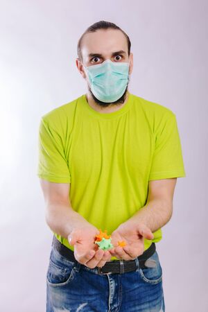 A guy in a green T-shirt holds out his hand with a coronavirus. Dirty hands.の写真素材