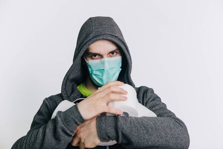 A guy in a gray sweatshirt and with rolls of toilet paper is standing on a white background. The excitement during quarantine for coronavirus.の写真素材