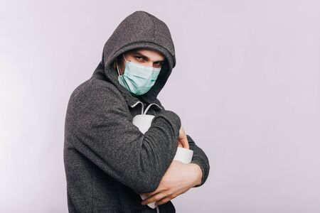 A guy in a gray sweatshirt and with rolls of toilet paper is standing on a white background. The excitement during quarantine for coronavirus.の写真素材